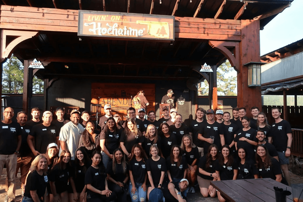 Torq team members gathered together at Camp Torq team-building event, wearing matching company t-shirts in a casual outdoor setting